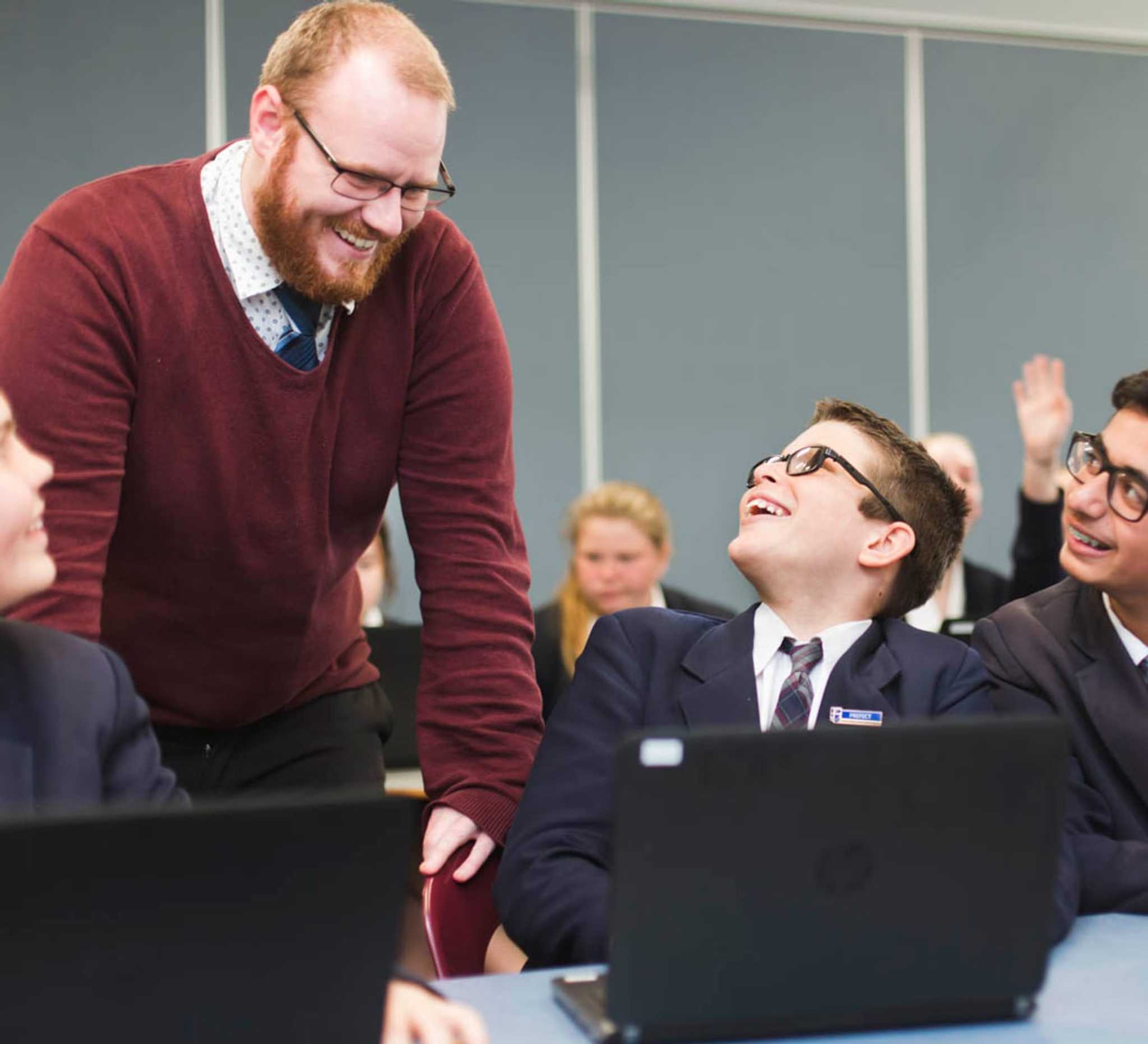 happy trainee teacher in red sweater interacting with student