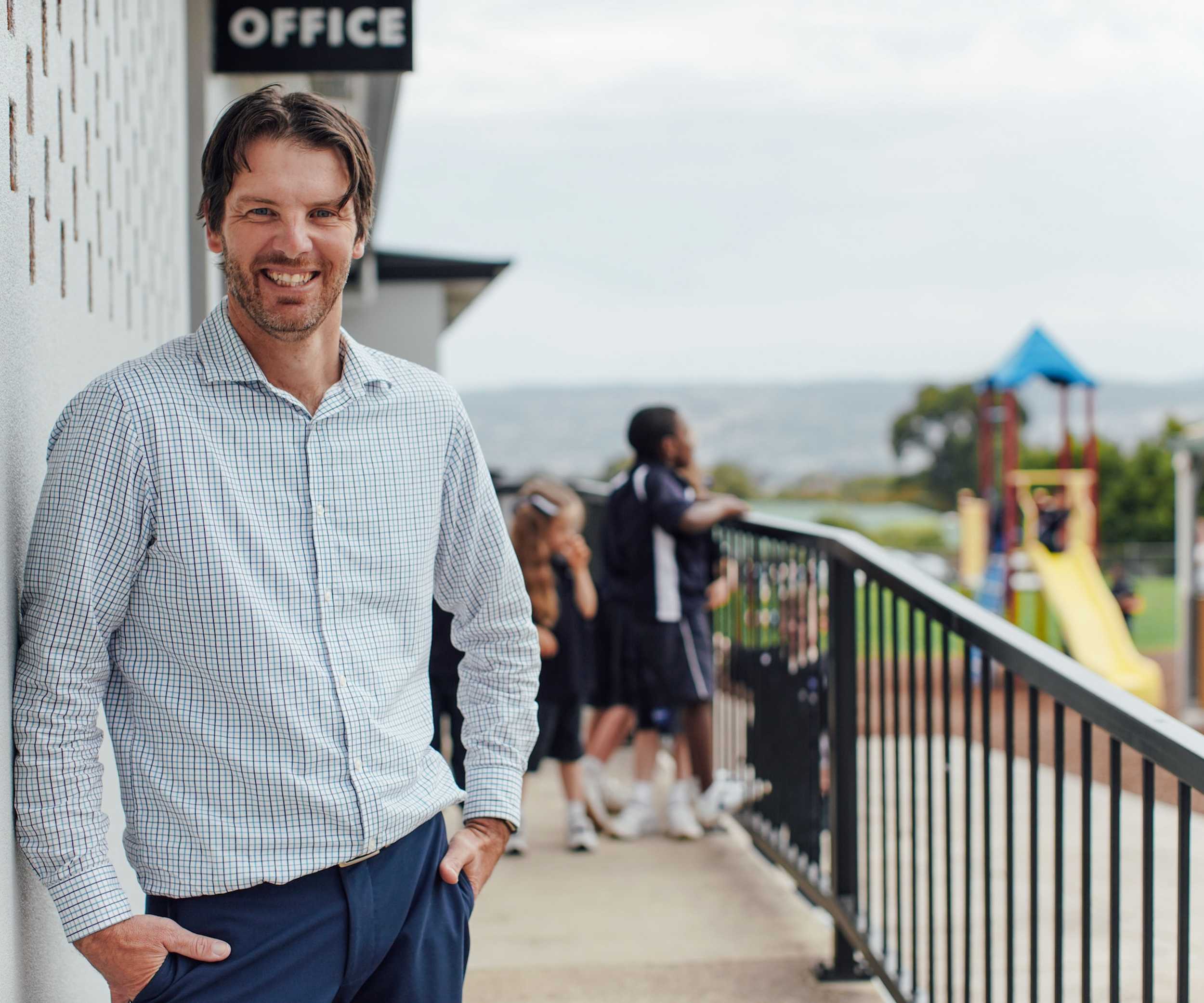 smiling school principal leaning against wall